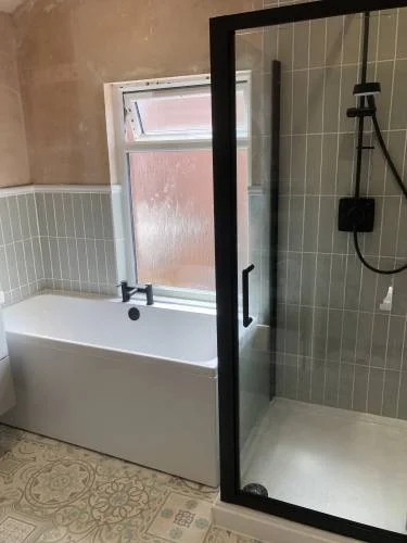 Bathroom with bath and black framed shower enclosure